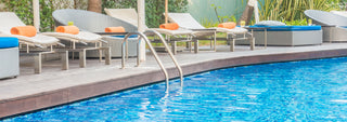 Hotel pool with clear blue water and various lounge chairs.